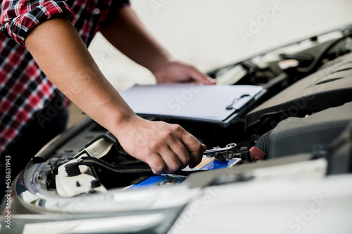 Close up of automotive mechanic using a wrench working auto repair in the garage, checking and maintenance service concept..