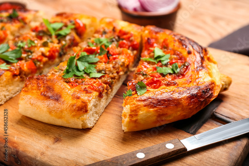 Board with sliced Turkish Pizza on wooden background