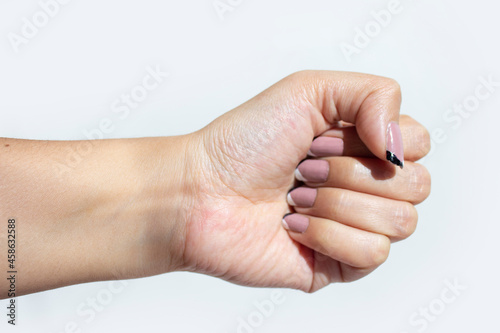 PUÑO DE MUJER FEMENINA CON MANICURE NEUTRO, CLOSE UP CON FONDO BLANCO