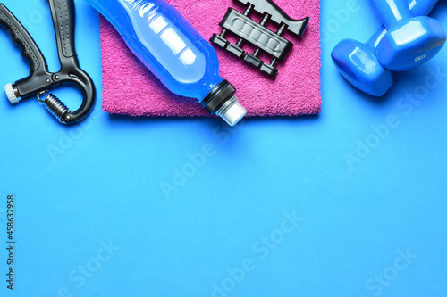 Manual training grip, dumbbells and various accessories, on a blue background. Zenith view and copy space.