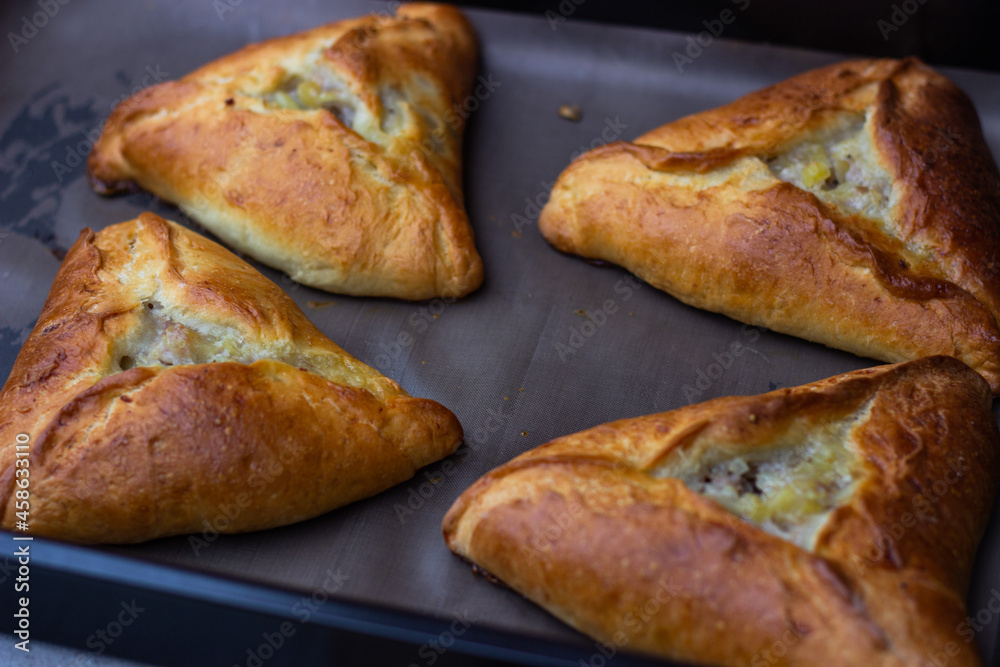 Photo of four ruddy triangular pies on a baking sheet, just taken out of the oven
Photo of four ruddy triangular pies on a baking sheet, just taken out of the oven