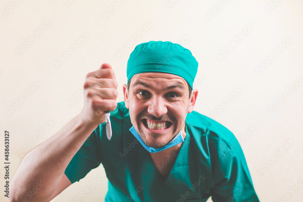 Angry doctor in green surgeon suit and protective breathing mask with lancet on the yellow background isolated Angry doctor in green surgeon suit and protective breathing mask with lancet on the yellow background isolated