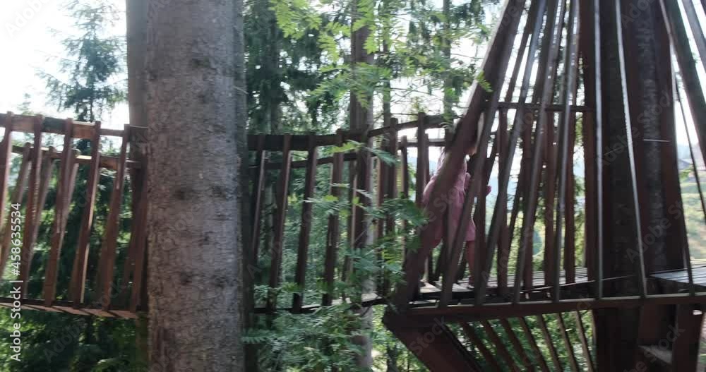 Cute little girl running on wooden footbridge and gesturing hello by waving her hand in the forest Cute little girl running on wooden footbridge and gesturing hello by waving her hand in the forest