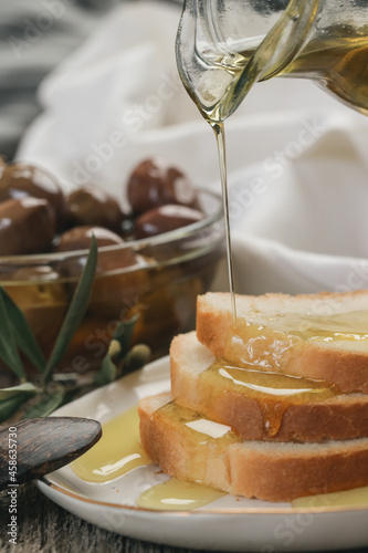 Woman pouring extra virgin olive oil on bread. Homemade helathy snack.	 photo