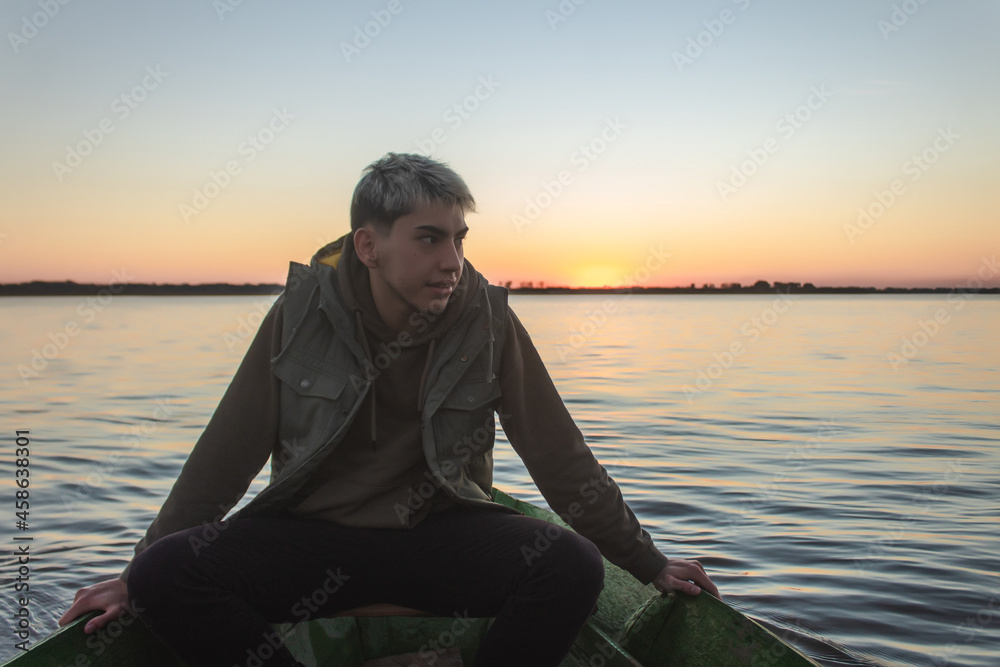 Handsome young man in a boat appreciating the sunset on the sea. Handsome young man in a boat appreciating the sunset on the sea.