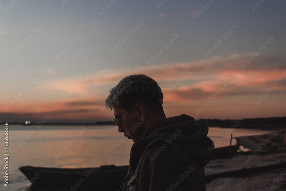 Young man watching the sunset on the abandoned beach.