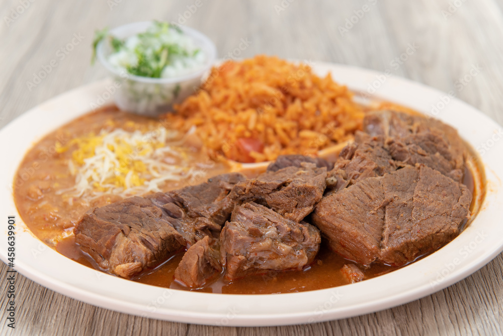 Birria beef meat, slow cooked to perfection on a plate with Mexican rice and beans for a hearty meal Birria beef meat, slow cooked to perfection on a plate with Mexican rice and beans for a hearty meal