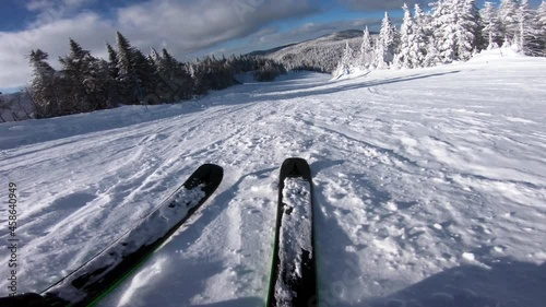 Skiing. Action camera low angle view of skis of skier going downhill on alpine ski on snow slopes in the mountains. Man going downhill on ski having fun on slopes. Winter sport outdoor activity video photo