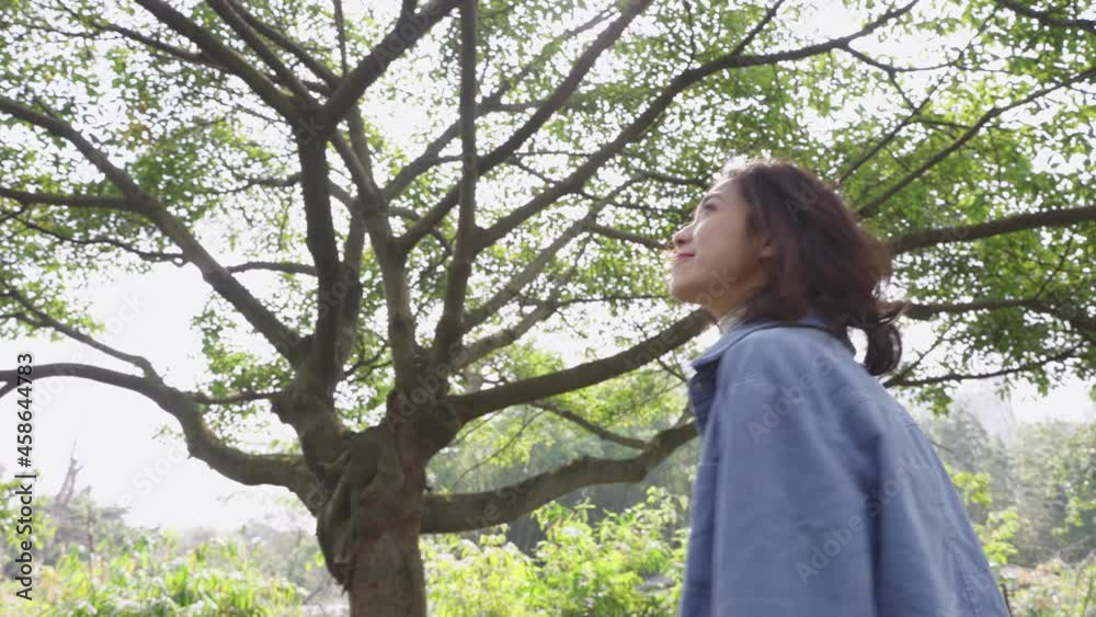 pretty young asian woman walking in the sunny park looking around enjoy the spring day pretty young asian woman walking in the sunny park looking around enjoy the spring day
