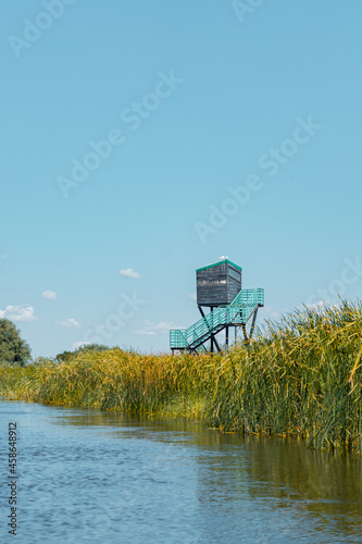 Vertical of a wooden birdwatching small tower on the side of the lake against the blue sky photo