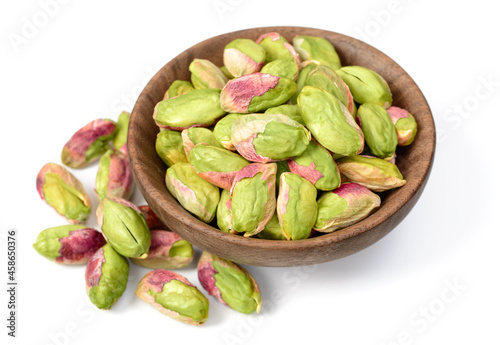 peeled pistachios in the wooden plate, isolated on the white background