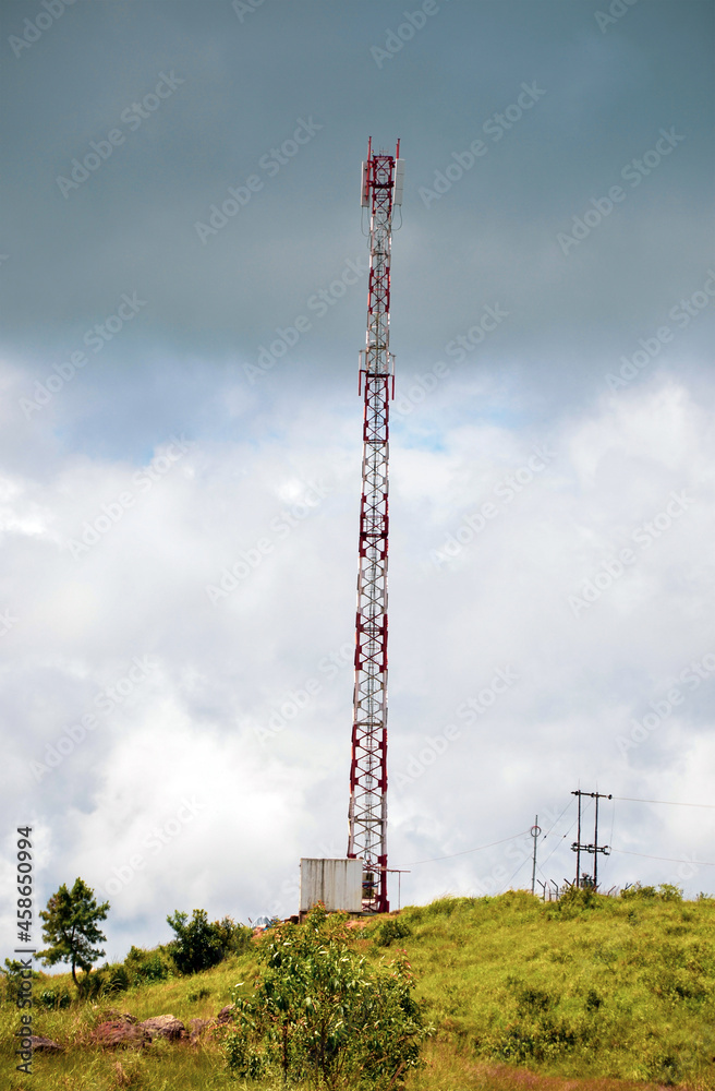 Telecommunication antenna or cell tower on a mountain in a dark cloudy sky in the background
