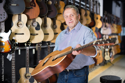 male demonstrates an acoustic guitar in a music store