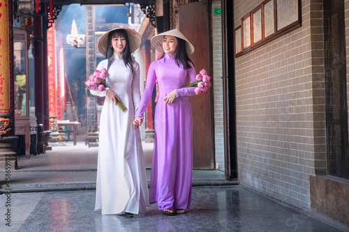 Young Vietnam woman wearing Ao Dai culture traditional at old temple at Ho Chi Minh in Vietnam,vintage style,travel and relaxing concept.