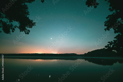 Reflections of starry sky in the lake. Dark night in the forest with the river. Still weather at night