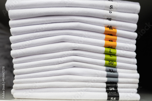 Stack of white t-shirts on shelf in a shop