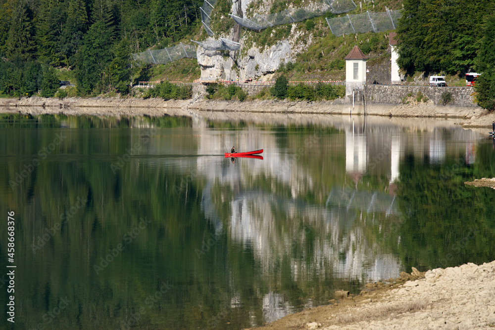 Fototapeta premium Fisherman in red canoe on a sunny late summer morning on Lake Klöntal. Photo taken September 4th, 2021, Klöntal, Switzerland.