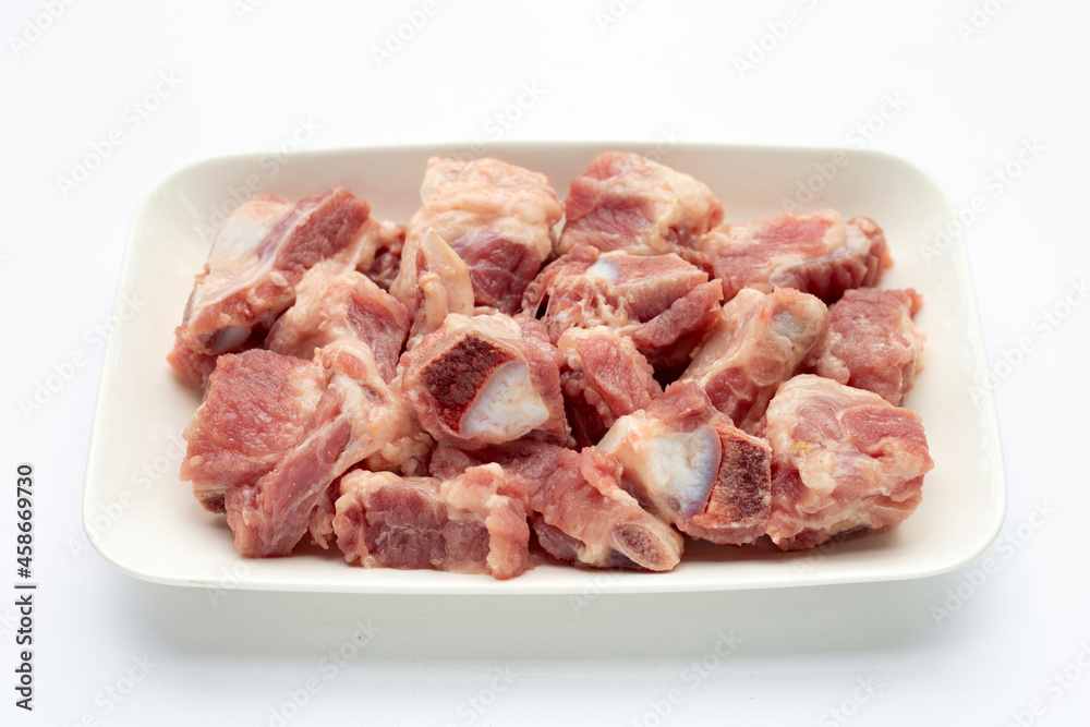 Raw pork ribs in white plate on white background.