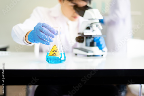 Scientist asian man using microscope with metal lens for research covid-19 in laboratory