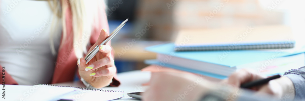 Female and male hands with pens with notebooks at work table Female and male hands with pens with notebooks at work table