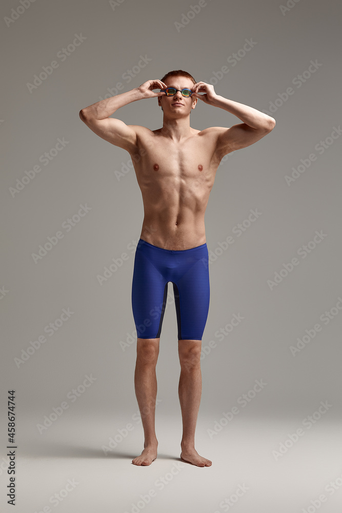 Portrait of a swimmer in mask, full-length portrait, young athlete swimmer wearing a cap and mask for swimming, copies of space, gray background Portrait of a swimmer in mask, full-length portrait, young athlete swimmer wearing a cap and mask for swimming, copies of space, gray background