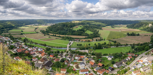 panoramic view of a valley with a small river making a u turn (loop) and a little village with cloudy sky 