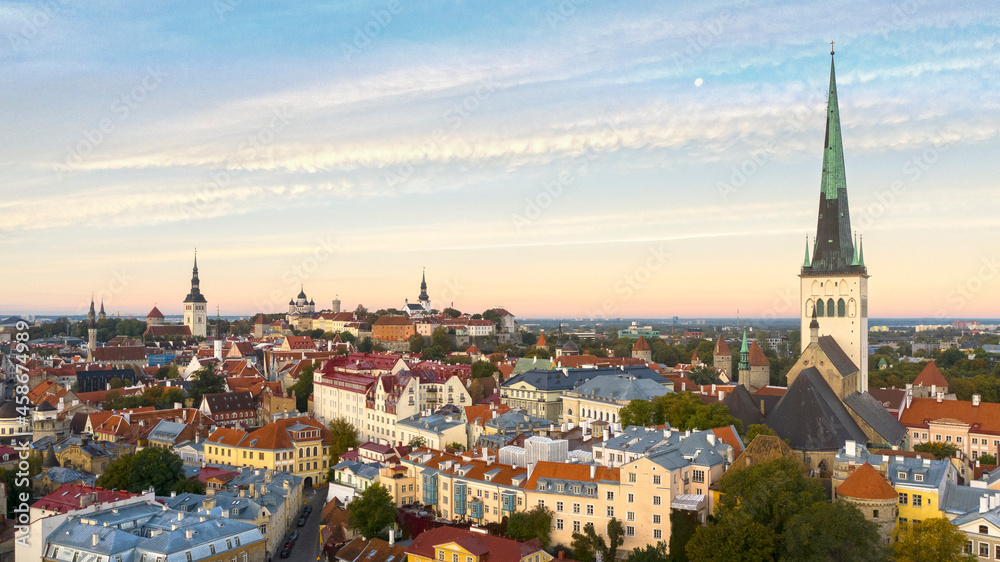 Aerial panoramic view over medieval Old Tallinn cityline with the sunrise colored sky and Moon background