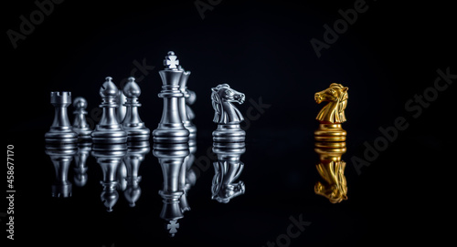 Chess board game between king silver team and golden team is stategy game as business challange competitive game ,this business stategy plan concept with black background.