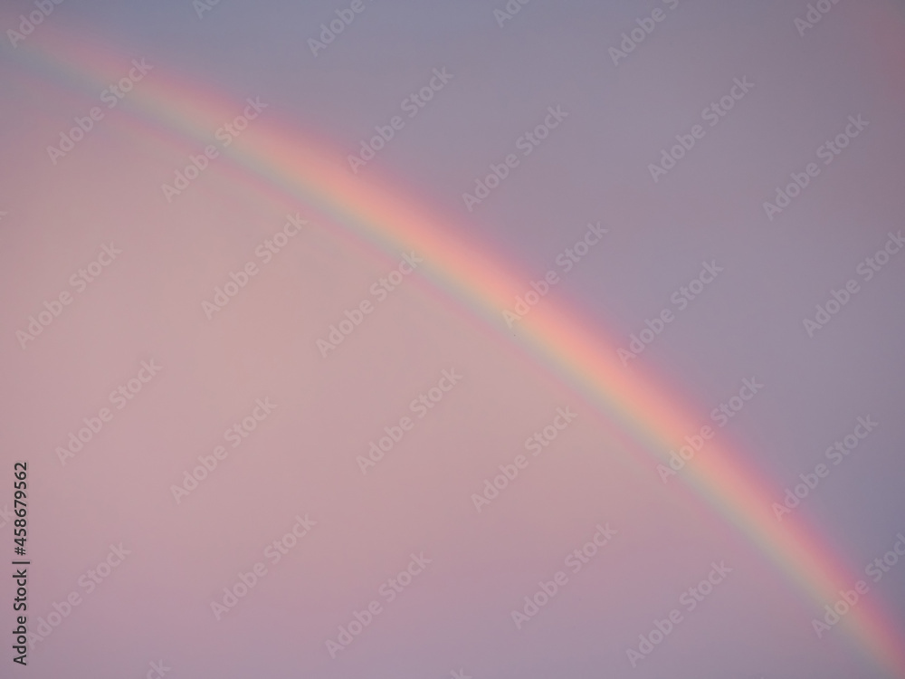 A large rainbow against a purple-pink sky. Close-up. Evening time after the rain. A large rainbow against a purple-pink sky. Close-up. Evening time after the rain.