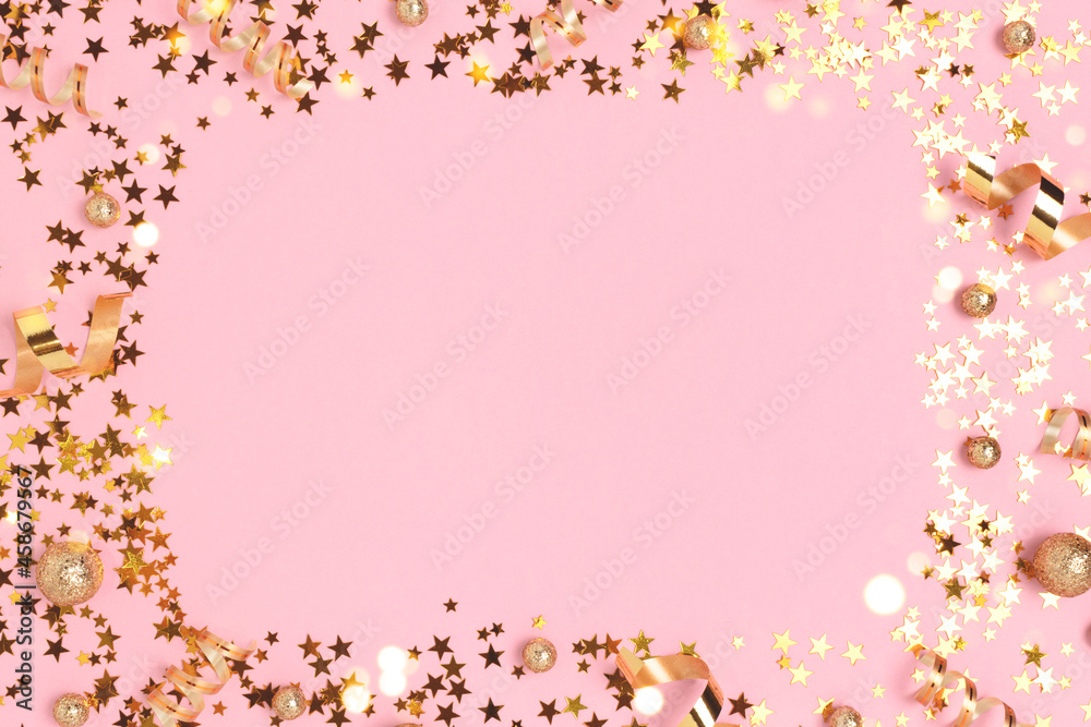 Border frame made of gold colored confetti on a pink pastel background.