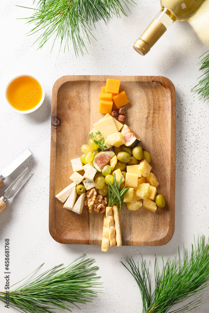 Christmas cheese platter with different cheese and grapes, nuts, olive, figs on a white background. Festive holiday food. Xmas brunch. Christmas cheese platter with different cheese and grapes, nuts, olive, figs on a white background. Festive holiday food. Xmas brunch.