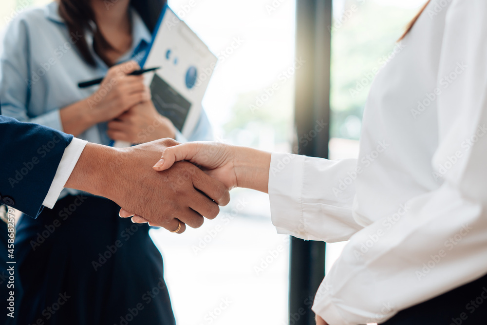 Fototapeta premium Young business people shaking hands in the office. Finishing successful meeting.