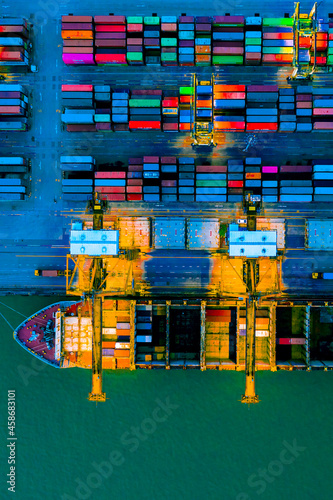 Fotografie Aerial top view over international cargo ship at industrial import-export port prepare to load containers with big container loader ship vessel
