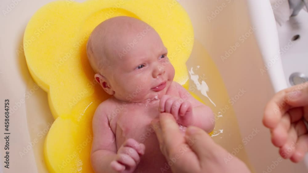 Baby is bathing in a children's bath, the mother washes her little