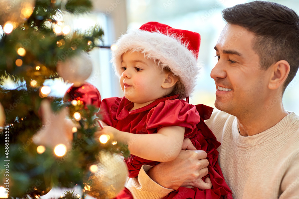 winter holidays and family concept - happy middle-aged father and baby daughter decorating christmas tree at home winter holidays and family concept - happy middle-aged father and baby daughter decorating christmas tree at home
