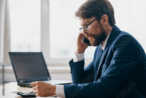bearded man sitting at a desk in front of a laptop stress anger official