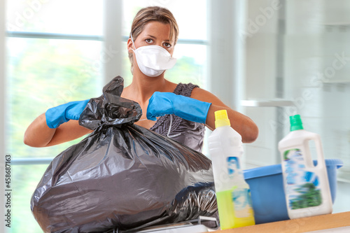 home hygiene-Young woman closing a garbage bag at home photo