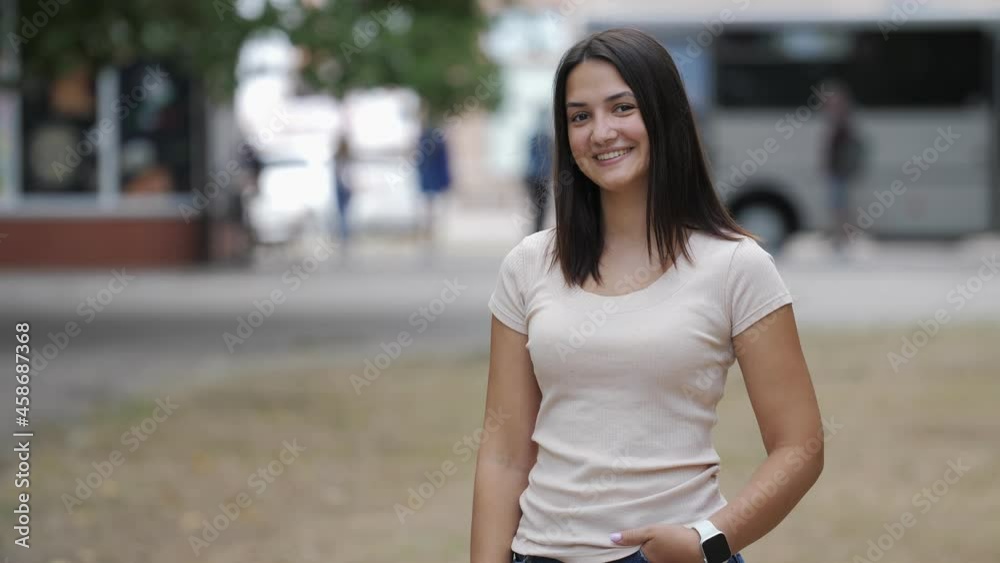 Jolly brunette girl with long hair dancing and smiling in green street in summer Jolly brunette girl with long hair dancing and smiling in green street in summer