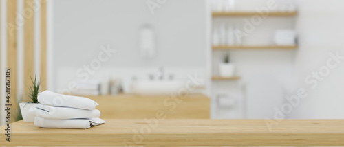 Cuadro en lienzo Wooden table top with bath towels over blurred white and wood minimalist bathroo