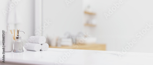 White table top with toiletries over blurred modern bright white bathroom