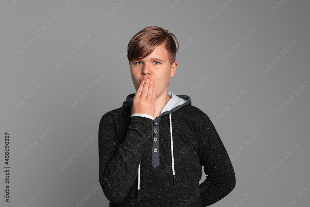 Oops emotion. Teen boy cover mouth with hand, looks at camera, stands over grey background, wearing in casual clothes Oops emotion. Teen boy cover mouth with hand, looks at camera, stands over grey background, wearing in casual clothes