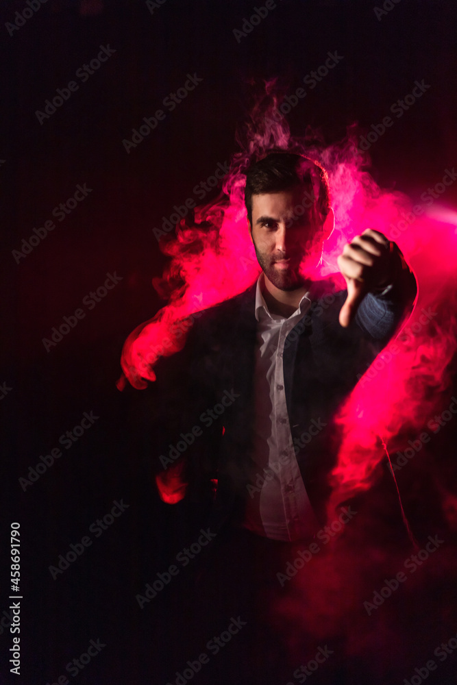 Photo of man wearing suit in pink smoke showing thumb down.