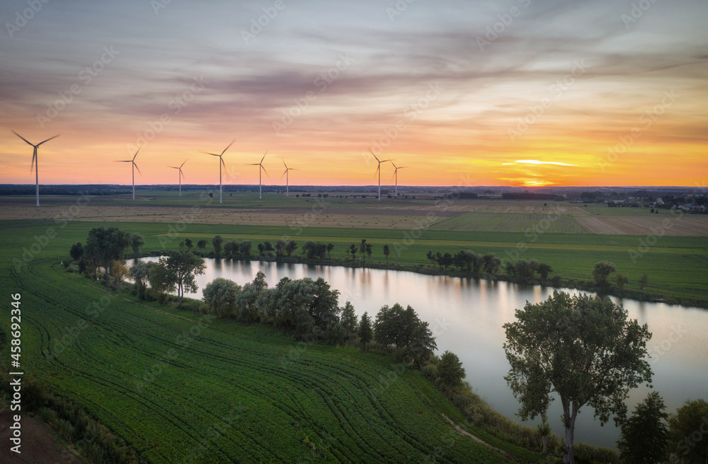 Obraz premium Amazing sunset over the field with wind turbines in Poland