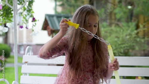Girl playing with soap bubbles outdoors. Happy child girl blowing soap bubbles. Blowing Bubbles in the Garden. Family lifestyle, outdoors activities, summer holidays with kids.  