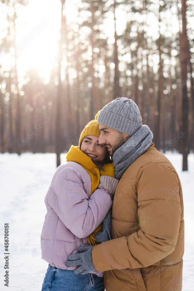 Positive young couple looking away in snowy park Positive young couple looking away in snowy park