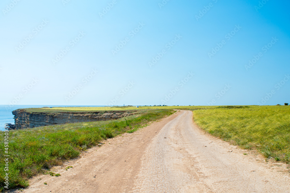 A country road, Green grass, azure water, clear blue sky. Landscape, nature