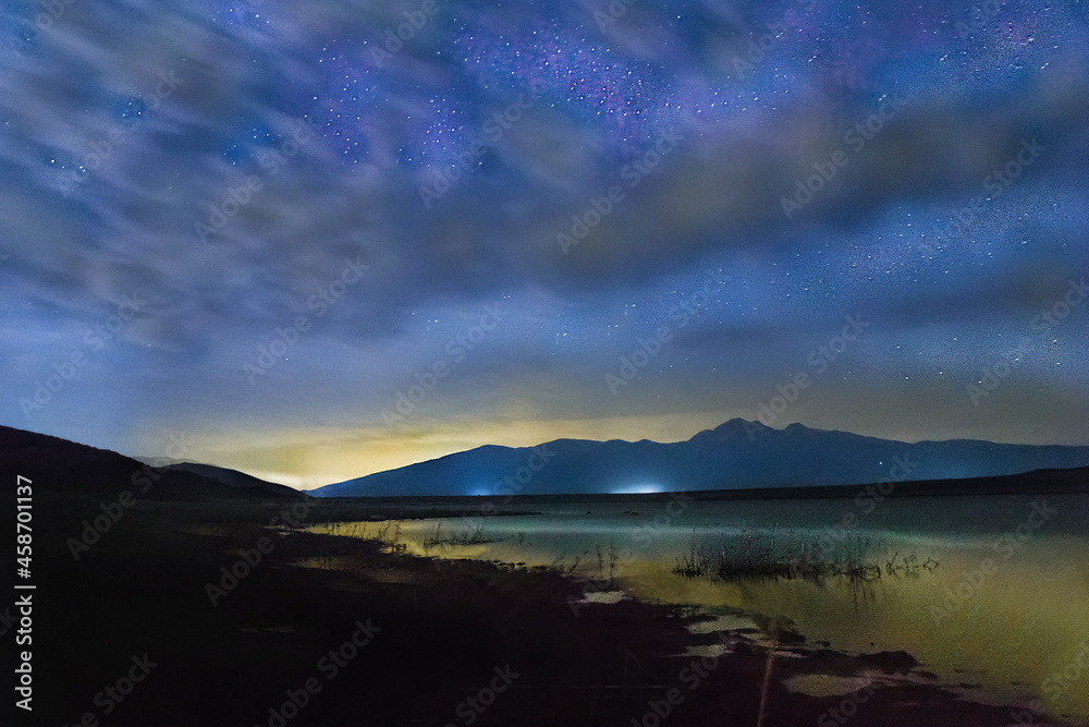 Fototapeta premium Sunset over the lake. Evening sky with clouds and stars over the lake.