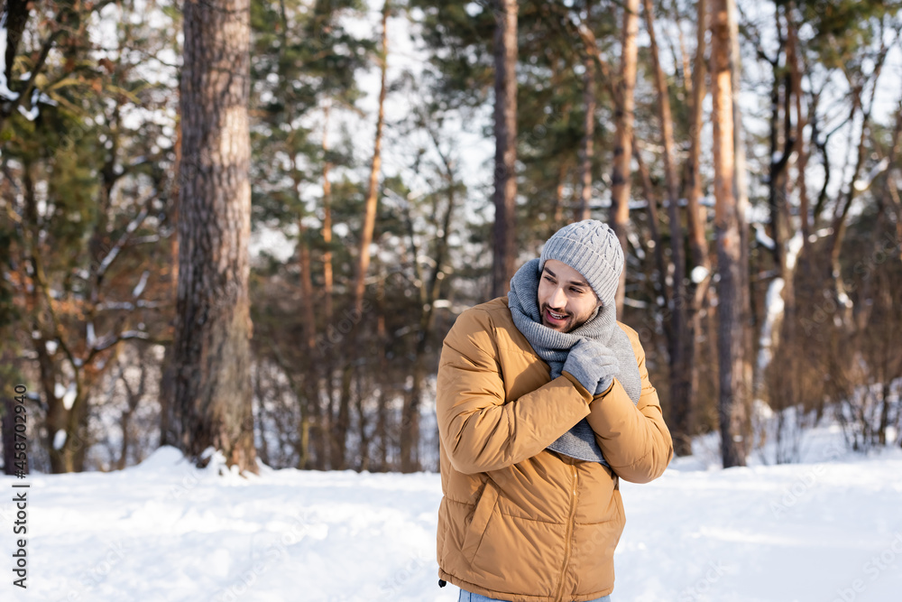 Smiling man in warm clothes standing in winter park Smiling man in warm clothes standing in winter park