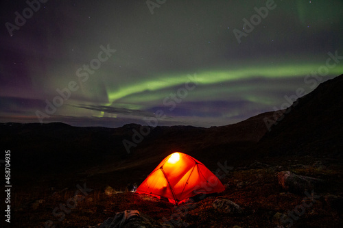 tent in the night under a ray of green light