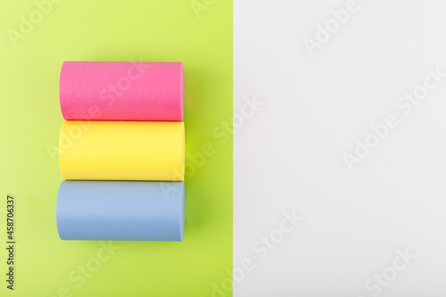 Flat lay with pansexual flag made of pink, yellow and blue rolls on light green and white background with copy space. Concept of pansexual community, sexual minorities, equal right and tolerance